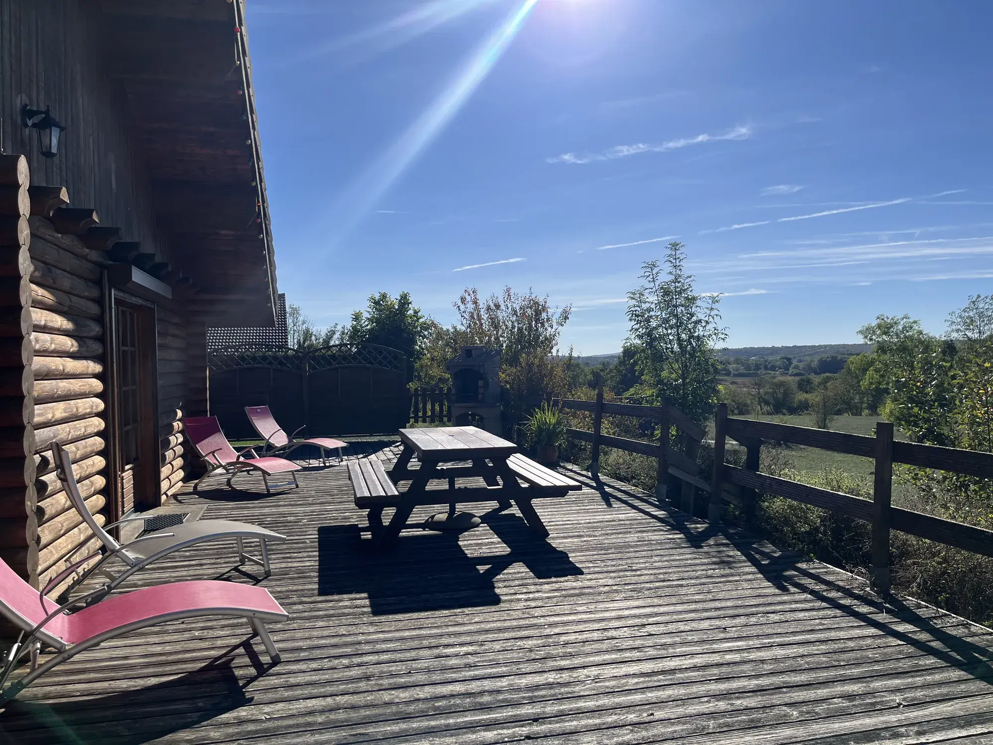 Grande terrasse en bois du Chalet Manon avec transats et vue sur la campagne